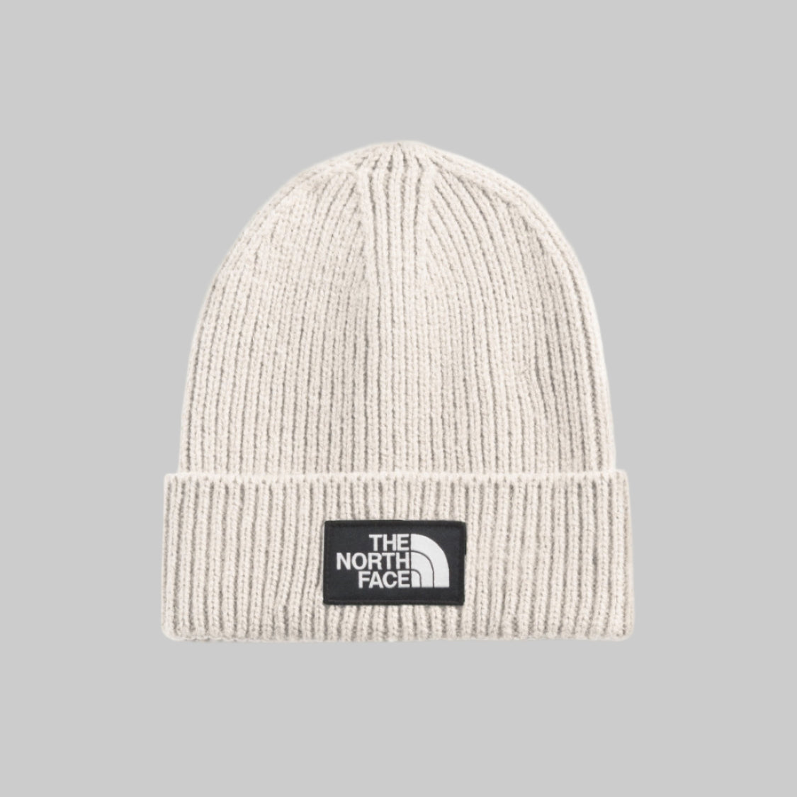 Beige knit beanie with The North Face logo on a light gray background